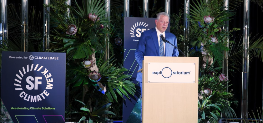 Al Gore is speaking from a podium at the SF Climate Week Conference sponsored by Climate Base.