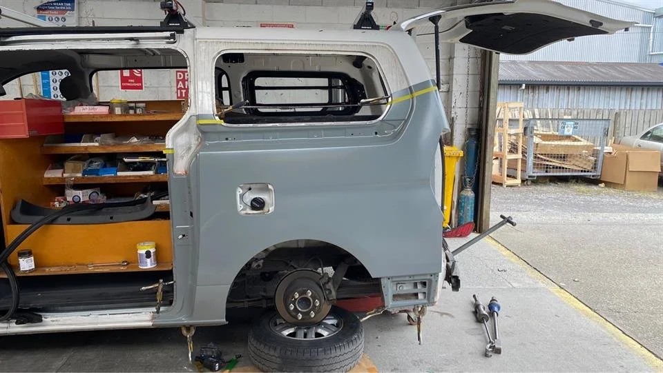 Van under repair in a garage with removed wheel and open rear door