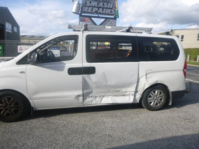 White van with side damage parked in front of repair shop