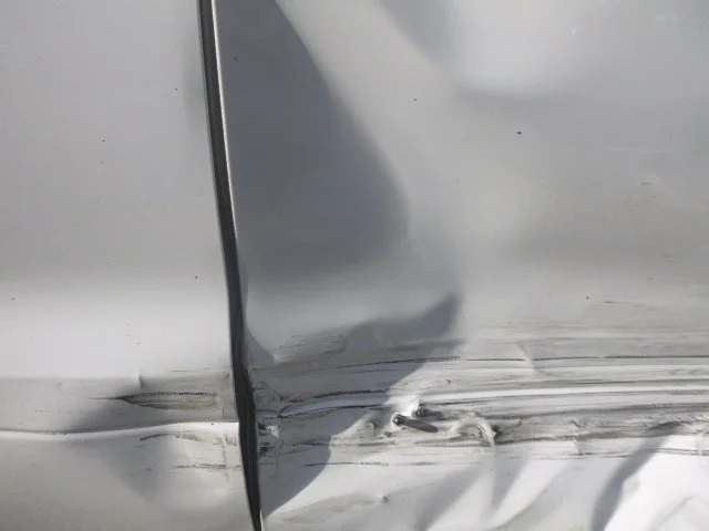 Close-up of car door with visible dents and scratches