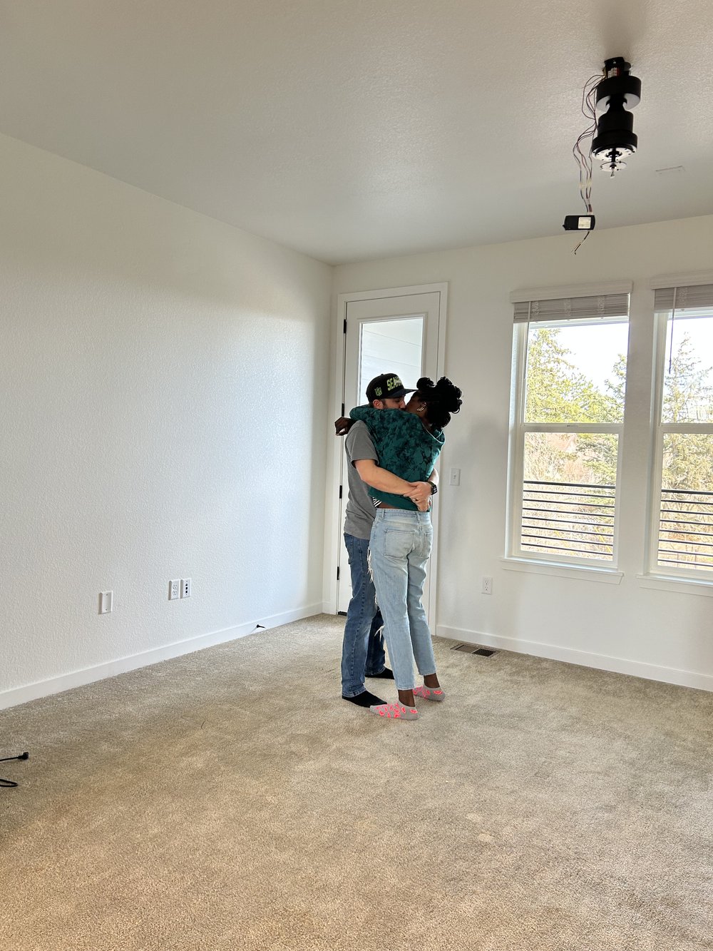 Newlywed interracial couple kissing in their new build dream home on move in day.