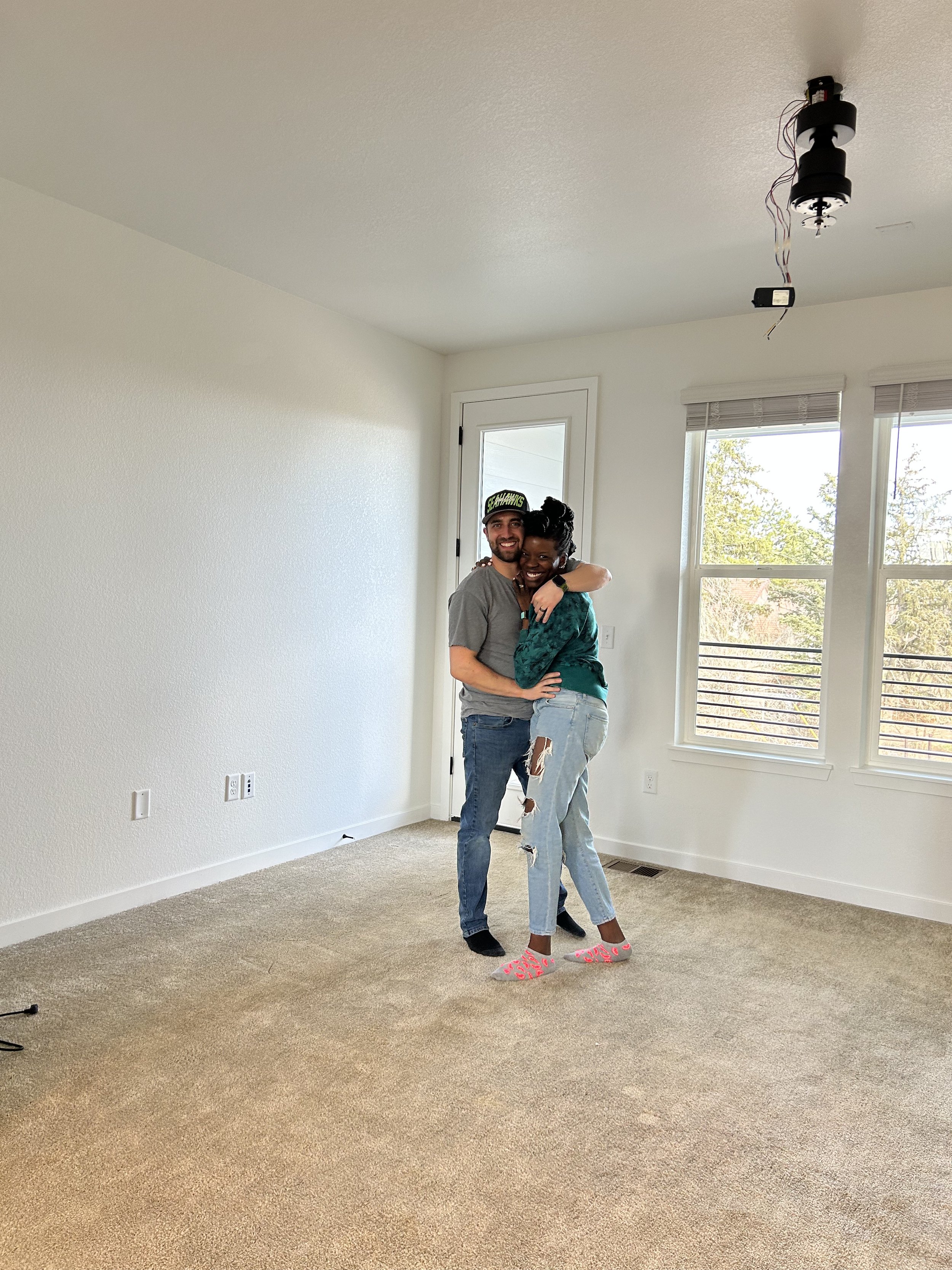 Newlywed interracial couple in their new build dream home on move in day.
