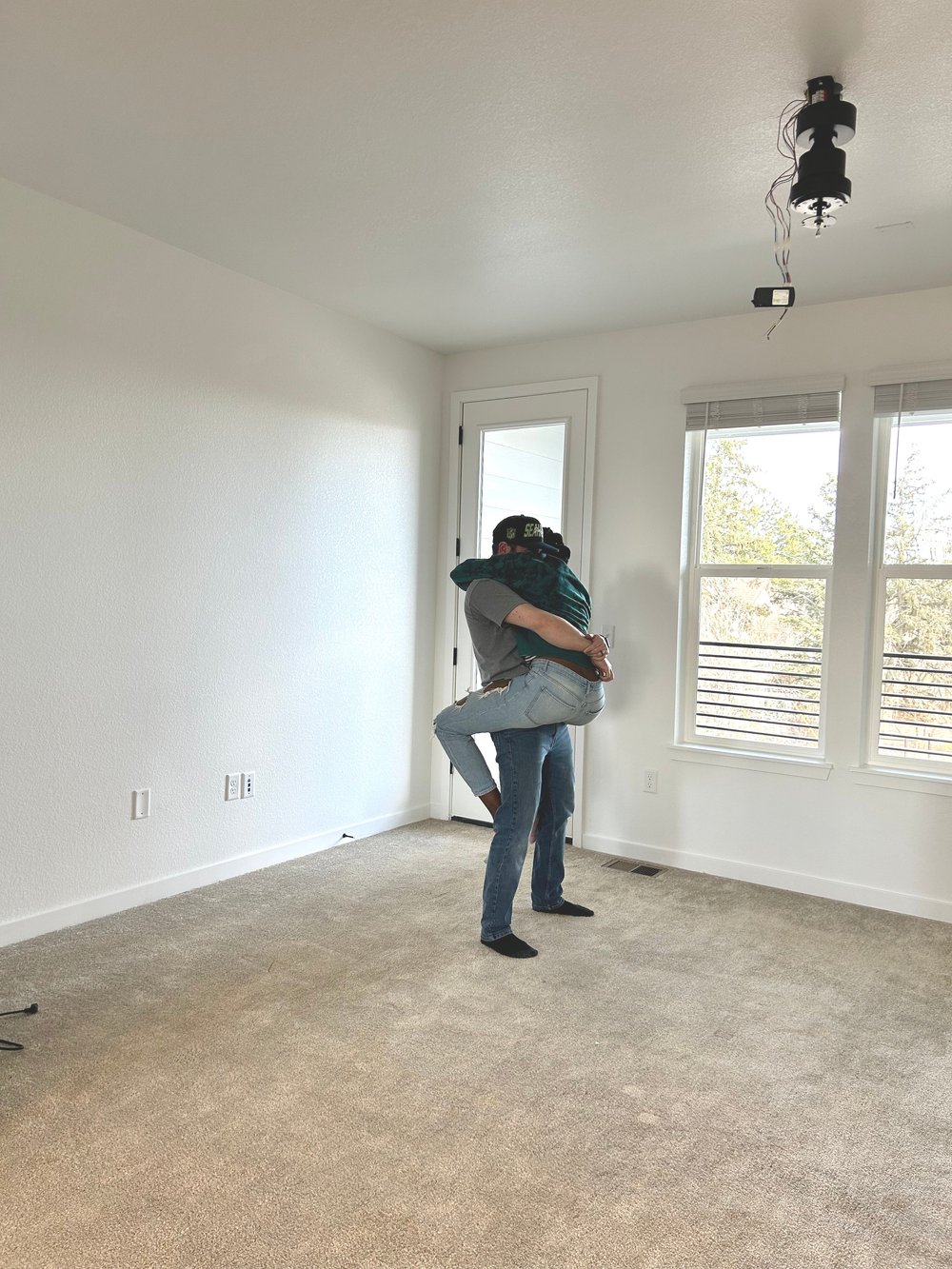 Newlywed interracial couple embracing in their new build dream home on move in day.
