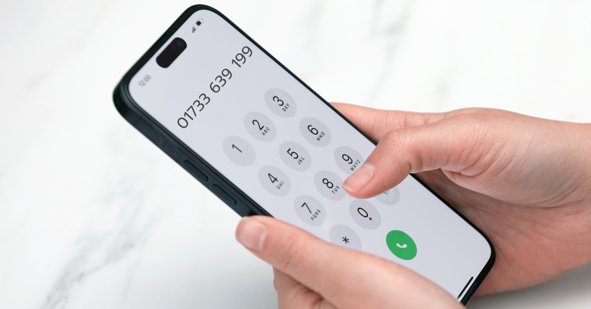 Close-up of a person dialing a phone number on a modern smartphone with a white background.