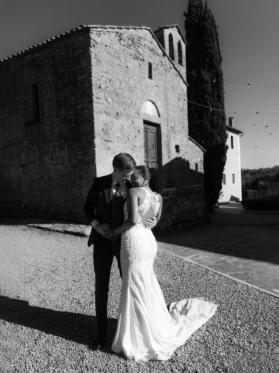Bride and groom kiss each other with a church in the background