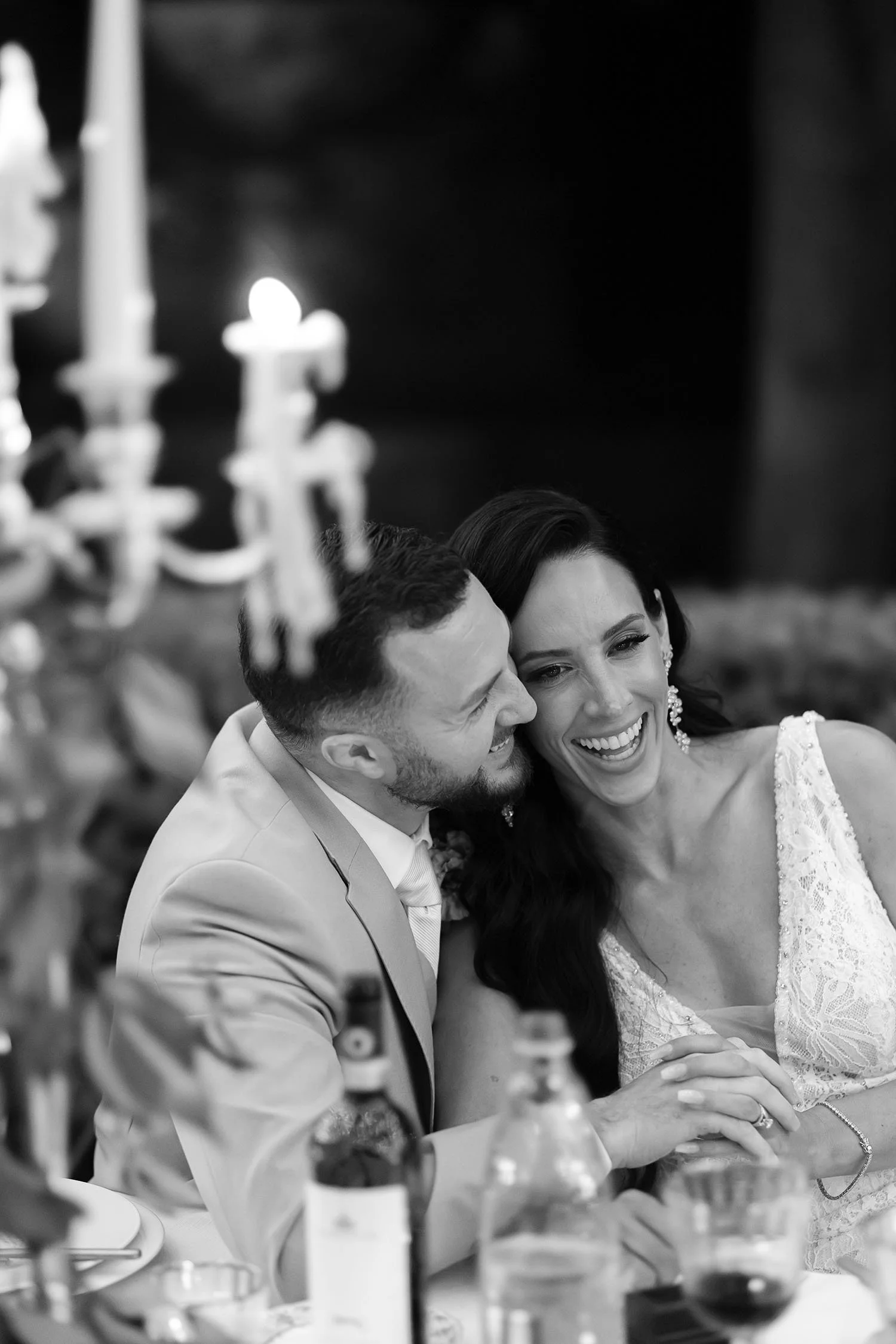 candid photo of the bride and groom sitting at the table by the candlelight