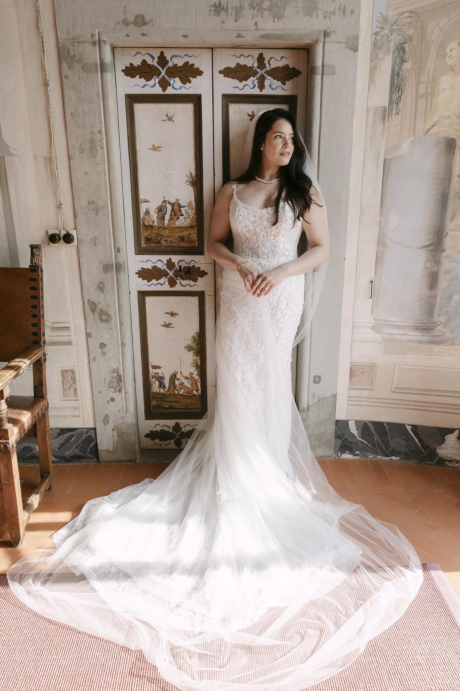 Bride standing against the door in a warm light with her dress