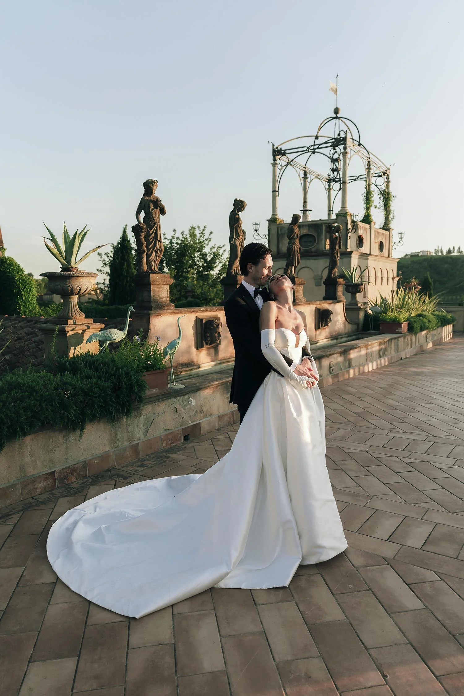 The bride and the groom on the terrace at Tenuta Corbinaia holding each other and looking into te sunset
