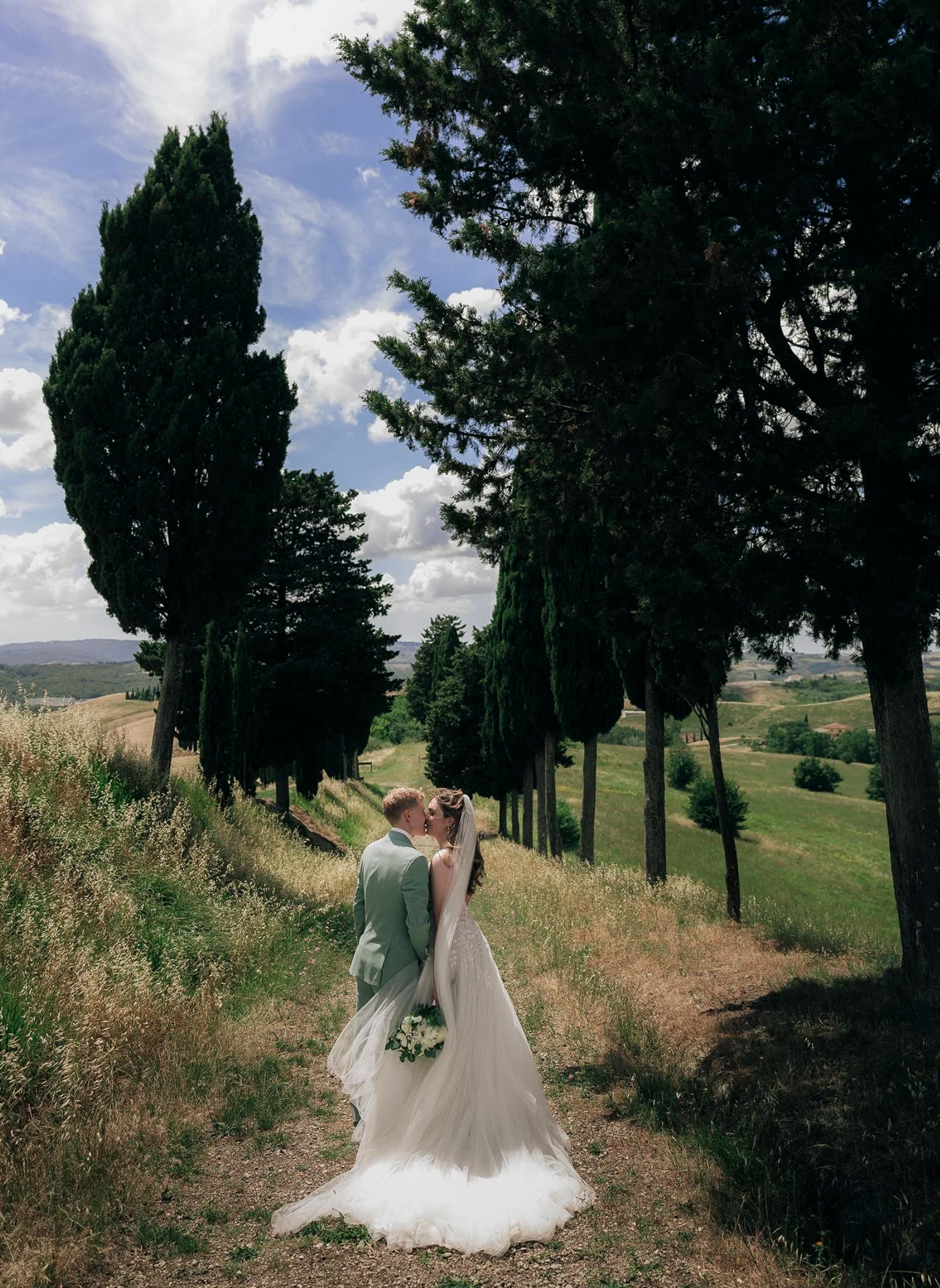 Bride and groom kissing each other along the trees near Certaldo
