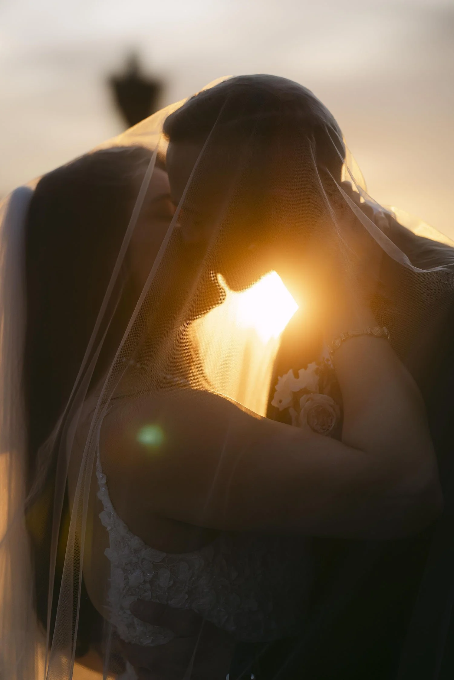 Silhouette of the bride and groom kissing at sunset