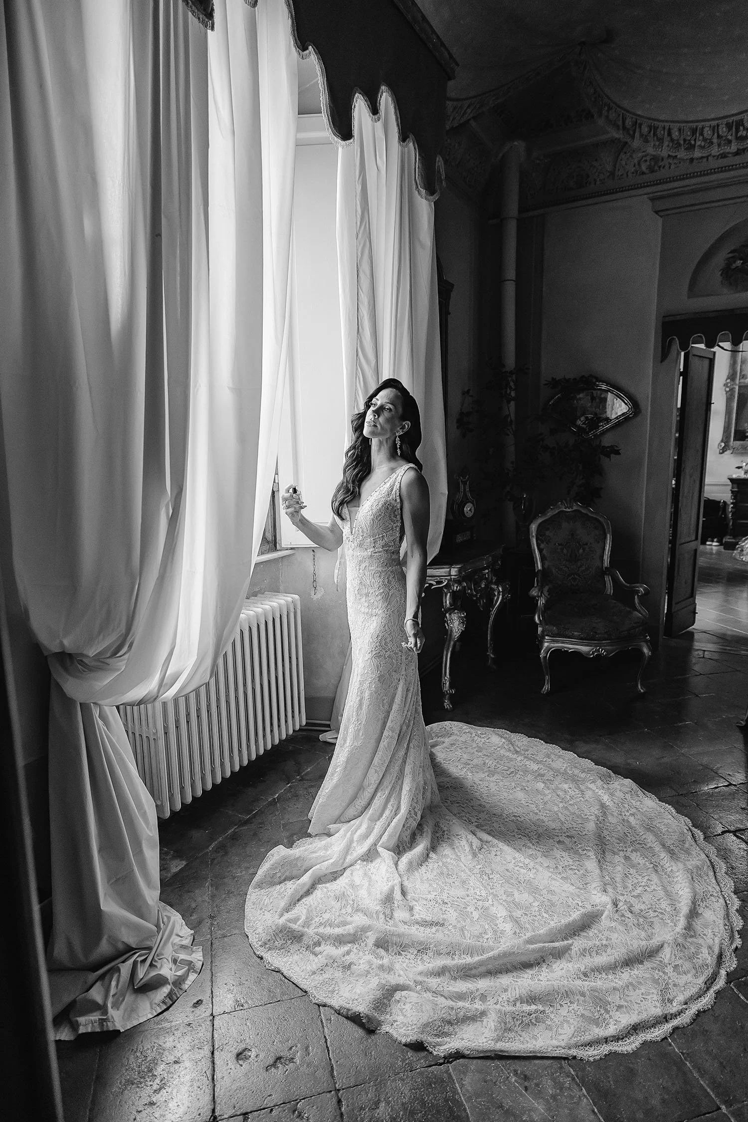 bride putting on her perfume by the window at Borgo Stomennano