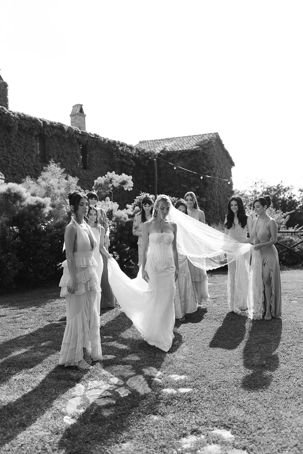 The bridesmaids help the bride fixing her dress and veil