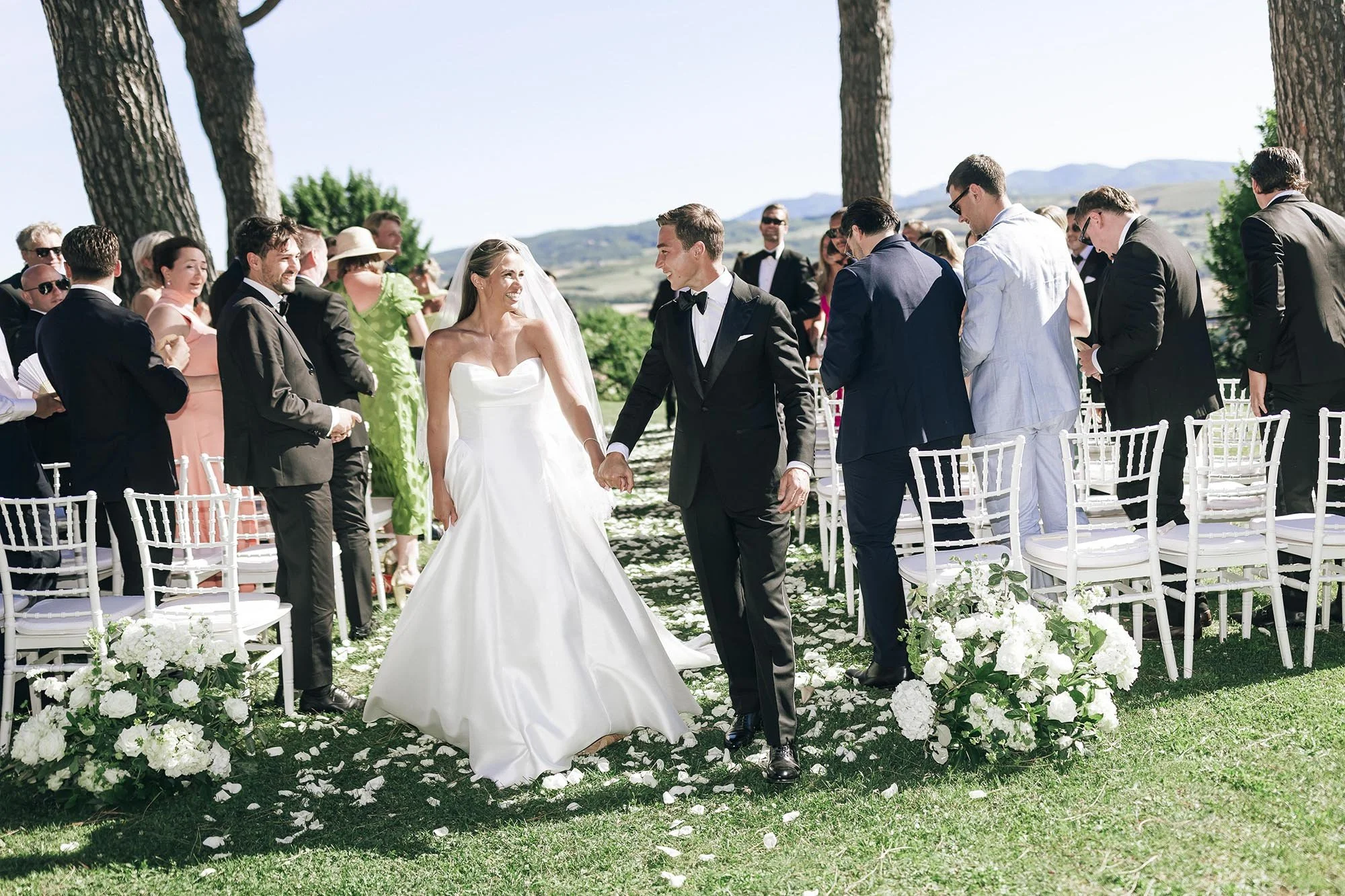 bride and groom walk down the aisle celebrated by their guests