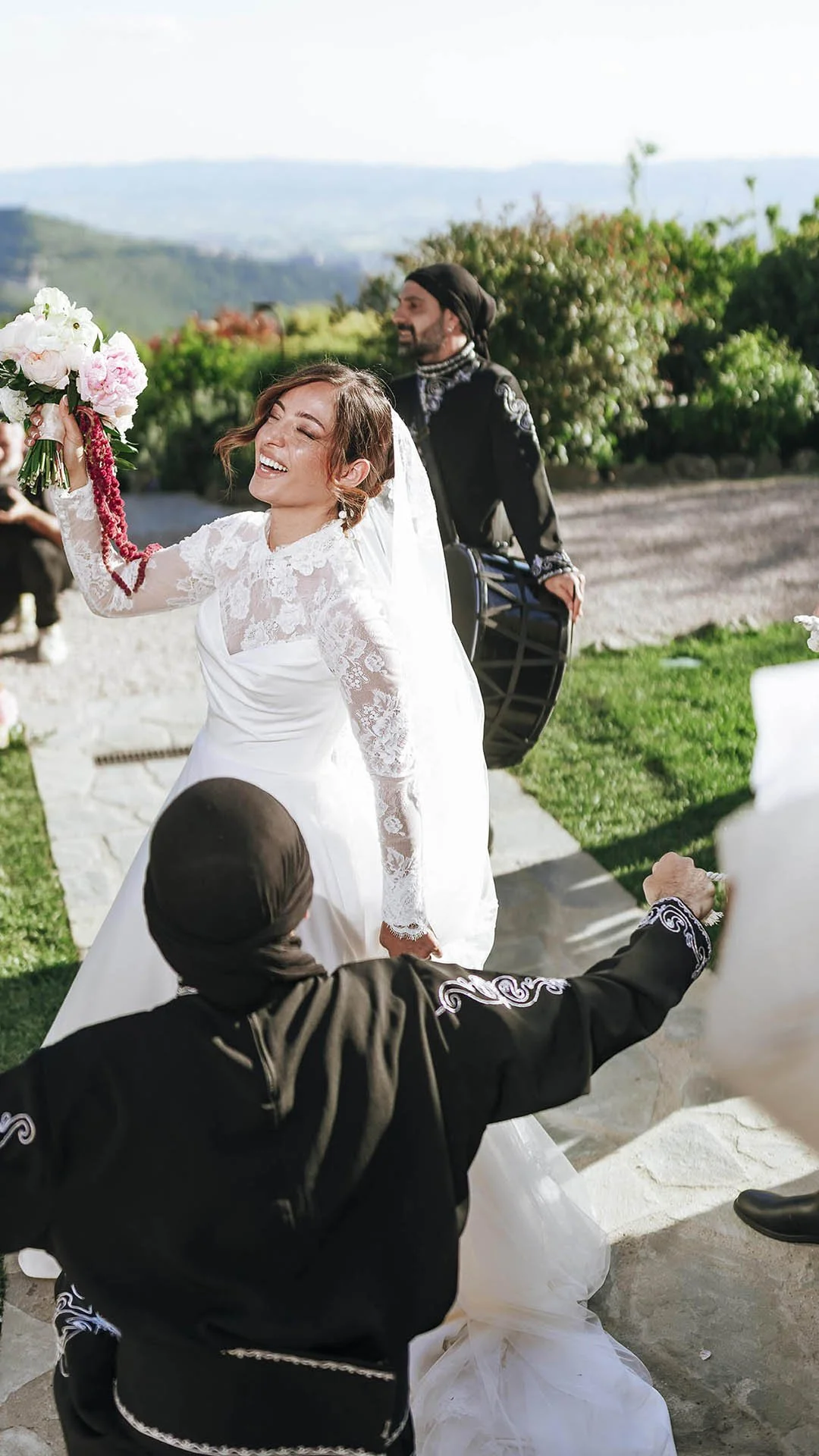 Iraqi bride dancing and holding her bouquet while drummers play during the reception at Castello di Petrata