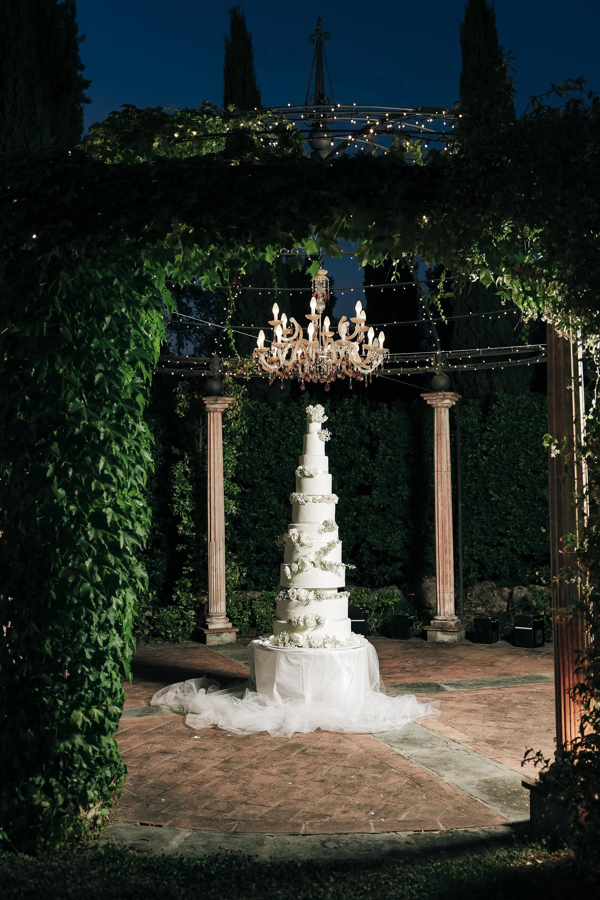 A very tall wedding cake under a lamp