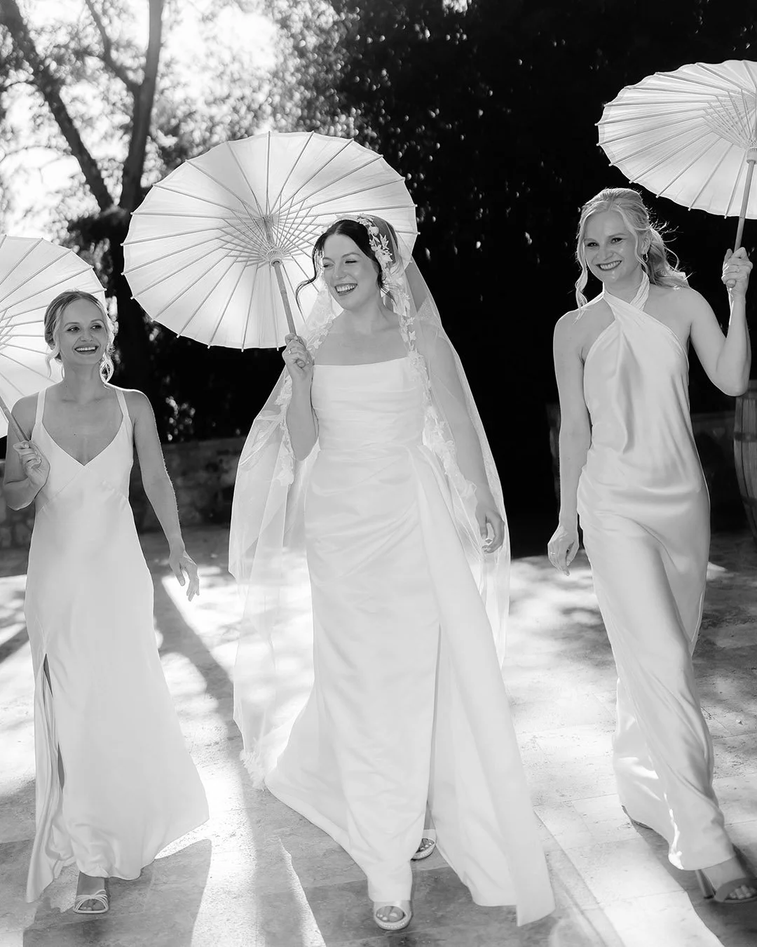 Bride walking with the bridesmaids holding parasoles