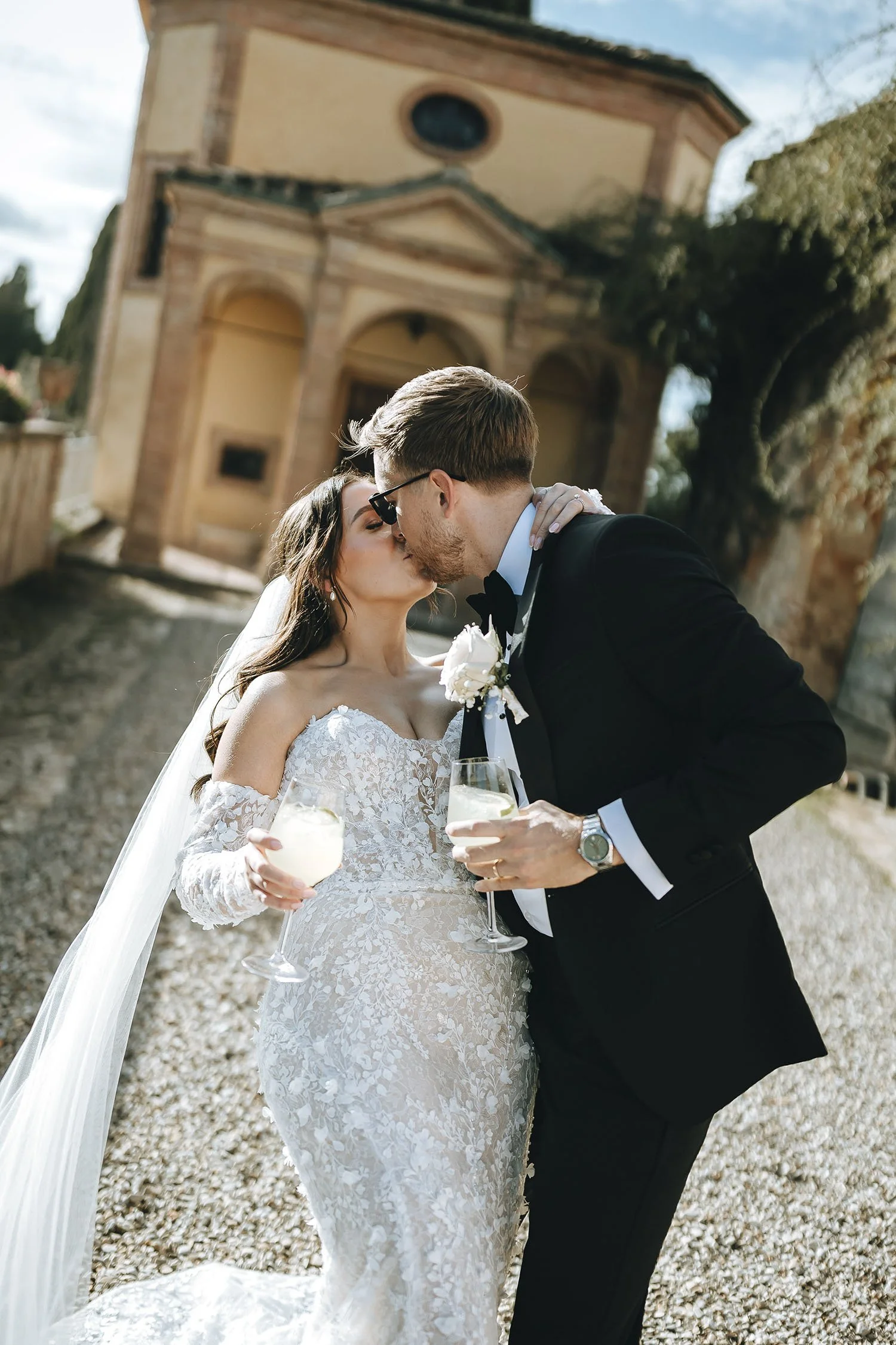 destination-wedding-tuscany-siena-villa-catignano-photographer. romantic kiss of bride and groom holding drinks