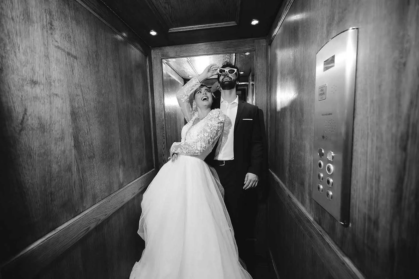 Editorial and timeless portrait of bride and groom playing joyfully with sunglasses in an elevator in a wedding venue in Umbria. Photo by Rellini art studio