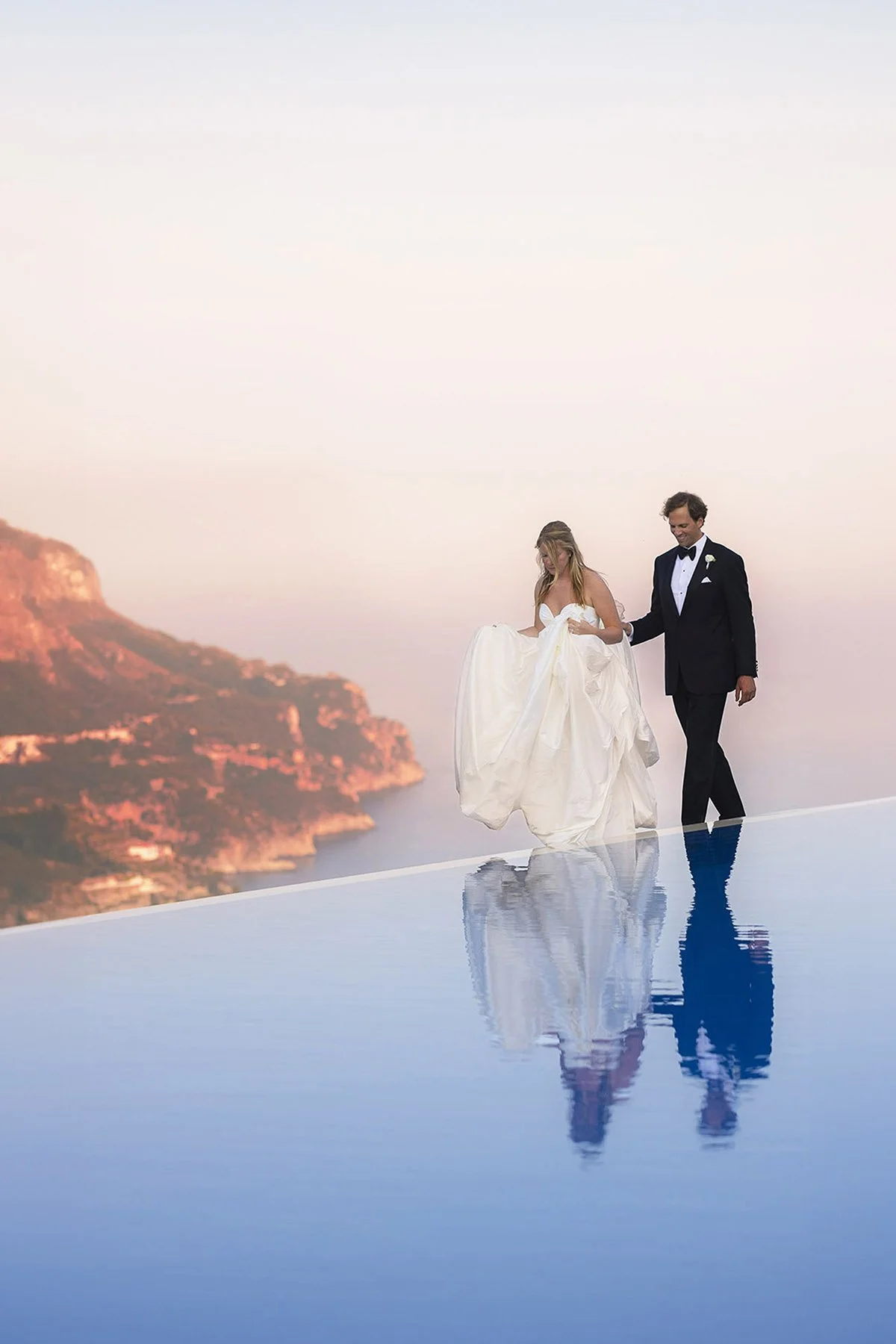 bride and groom walking together holding each other hands on the edge of a swimming pool in Ravello at Hotel Caruso Belmond