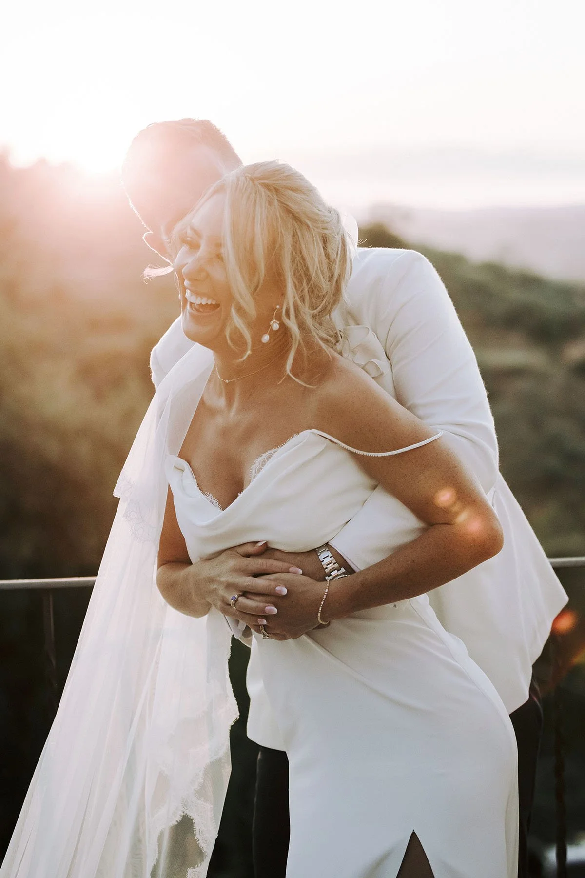 candid portrait of bride and groom holding each other at sunset