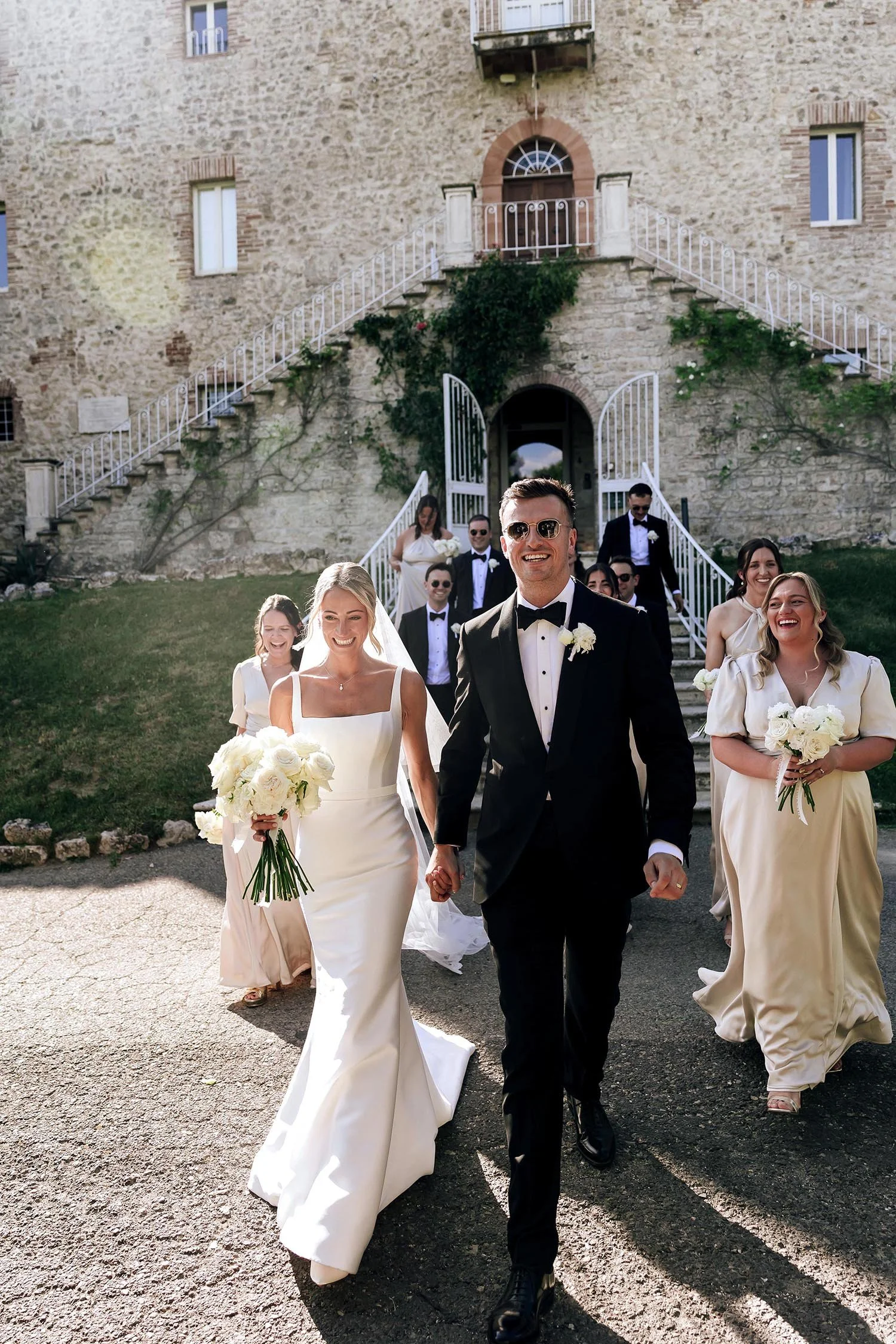 Bride and groom walking together with the bridal party following them