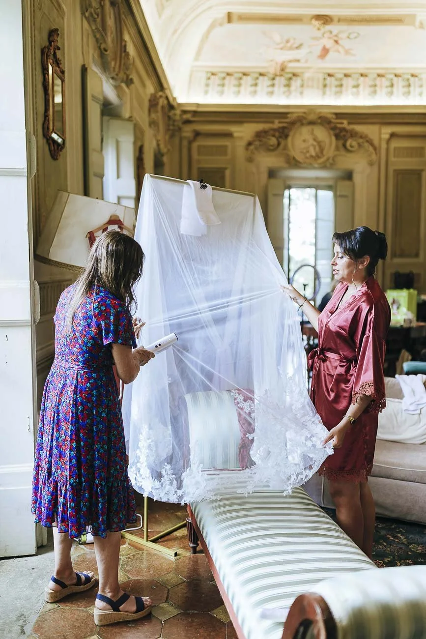 Destination wedding at Castello di Montegufoni in Florence, photo by Rellini art studio documentary wedding photographers in Tuscany. Moments of the getting ready in the bride room with the family fixing the dress