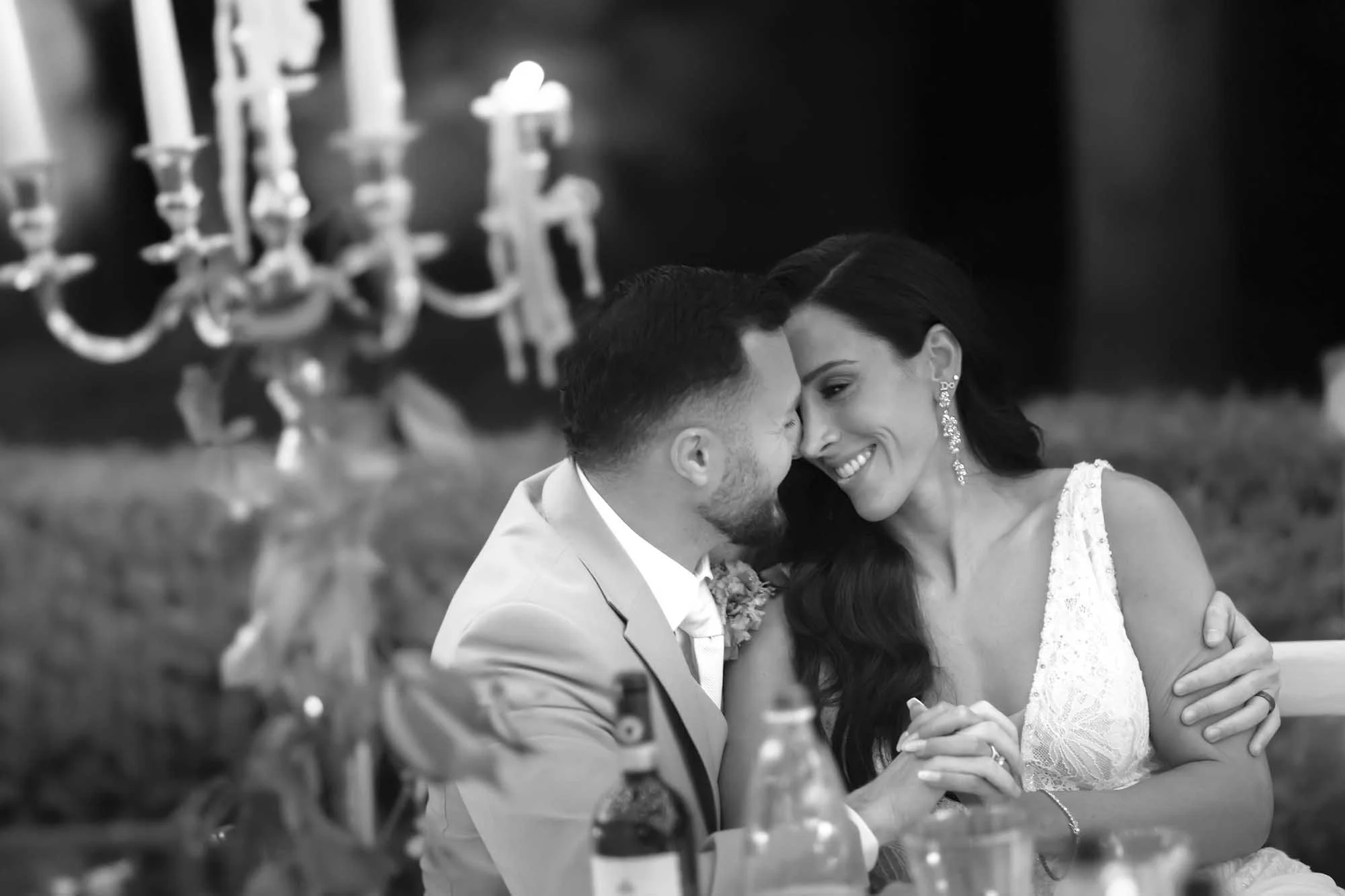 Candid photo of bride and groom looking tender and intimate at the dinner table  with candlelight