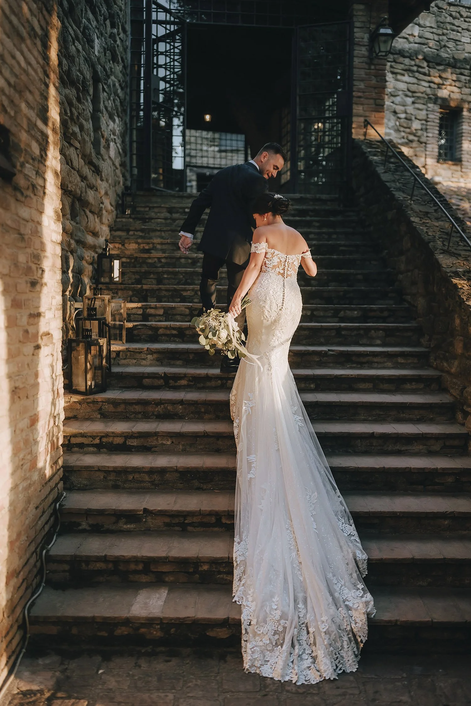 Groom helping the bride on the stairs of Castello di Rosciano