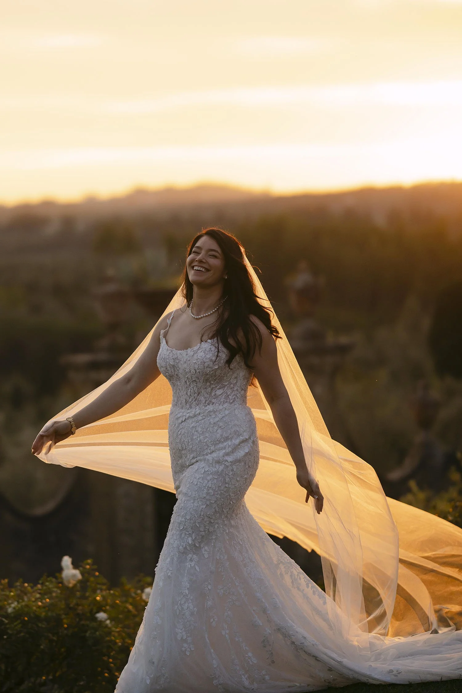 The bride walking alone holding the veil with a warm sunset light