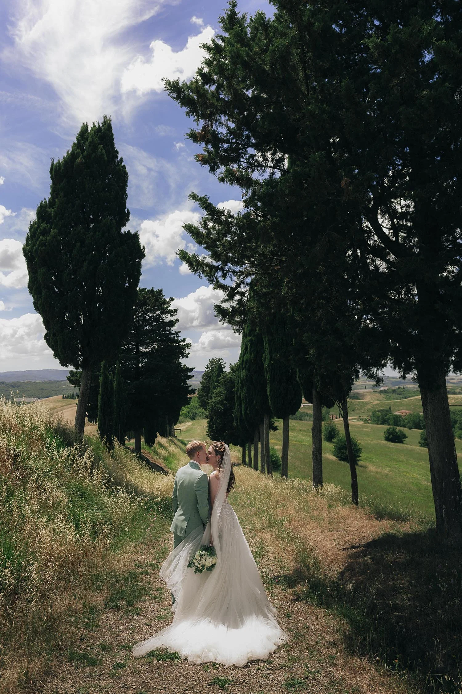Couple kissing each other along a path with high cypresses near Certaldo in Tuscany.