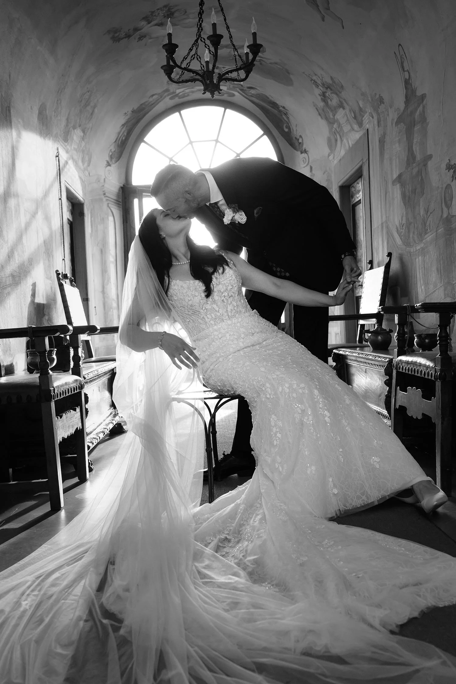 Groom kissing the bride seated on a chair 