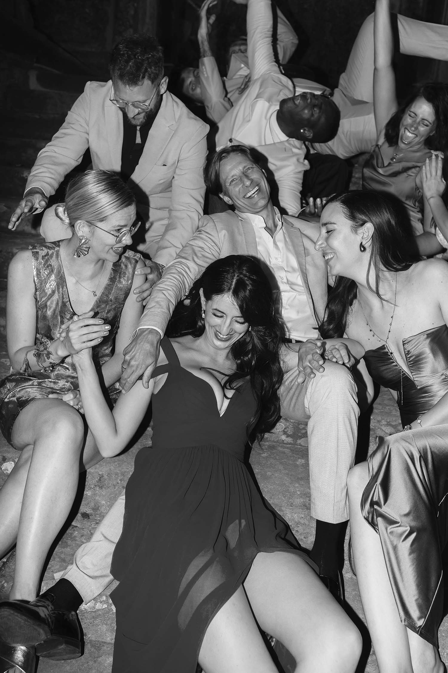 Bridal party sitting on the stairs and having a great time laughing and holding each other at Castello di Montegufoni in Tuscany. Photo by Rellini art studio best wedding photographer in Umbria