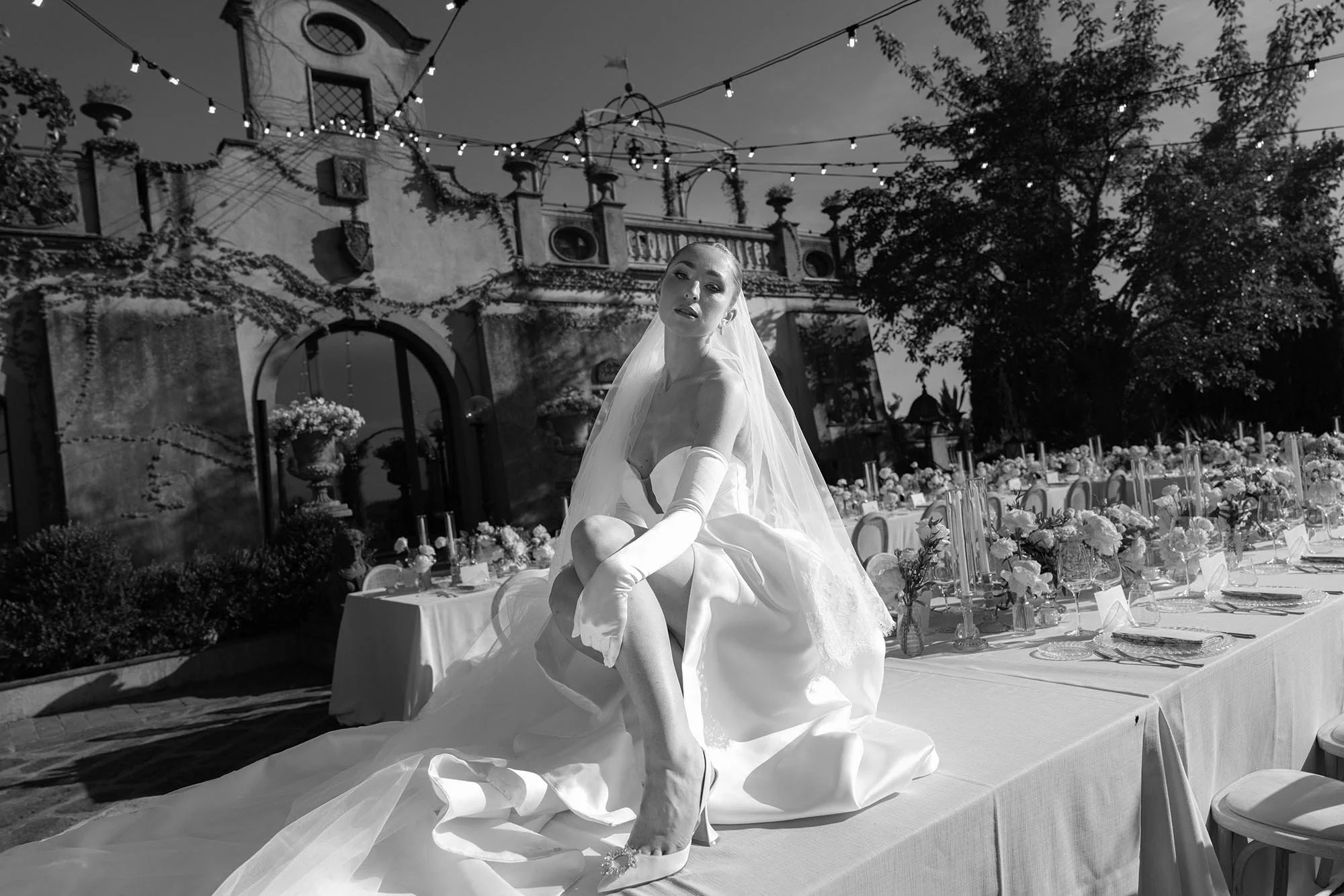 the bride sitting and posing on the dinner table at Tenuta Corbinaia