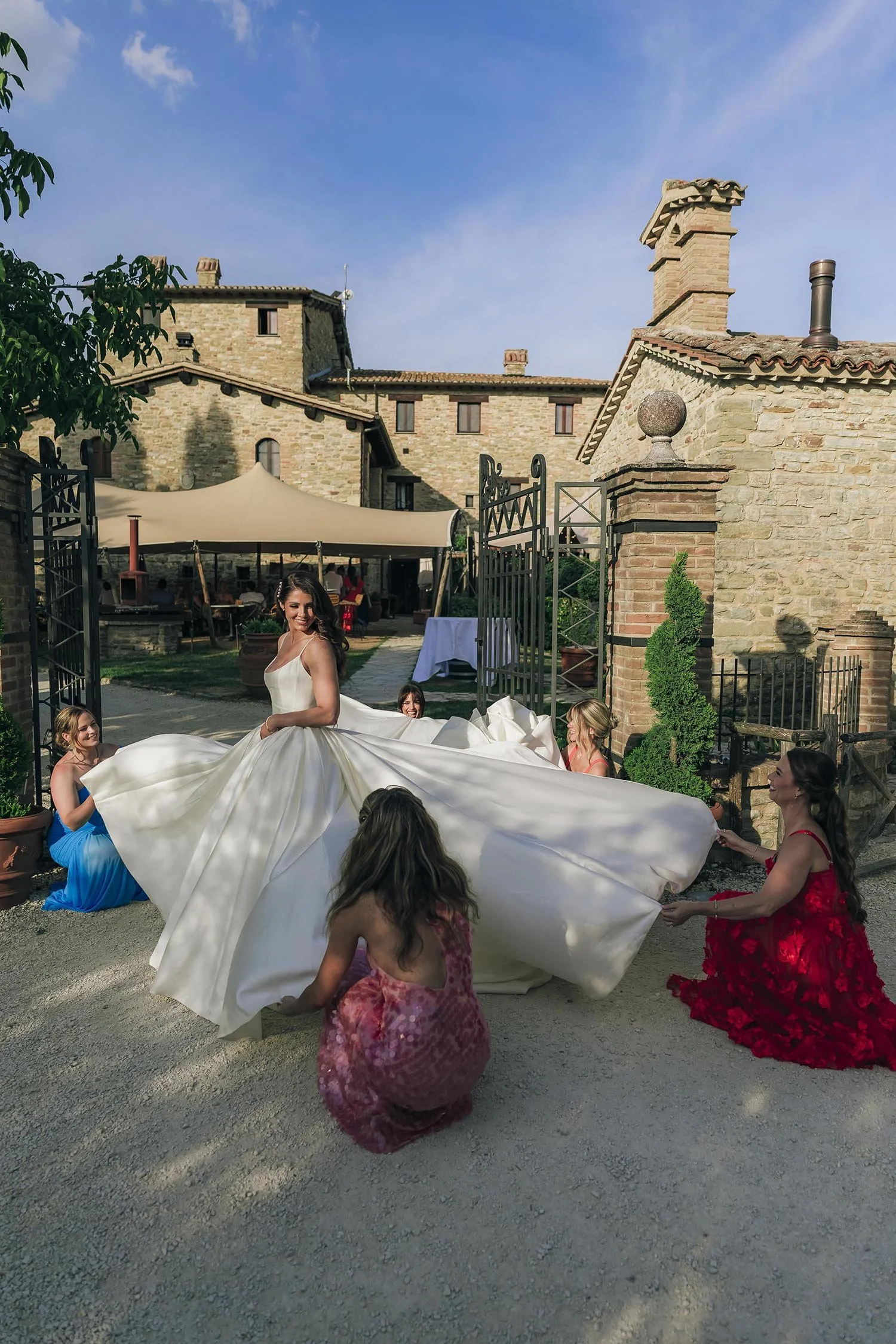 bridesmaids help the bride fixing her dress