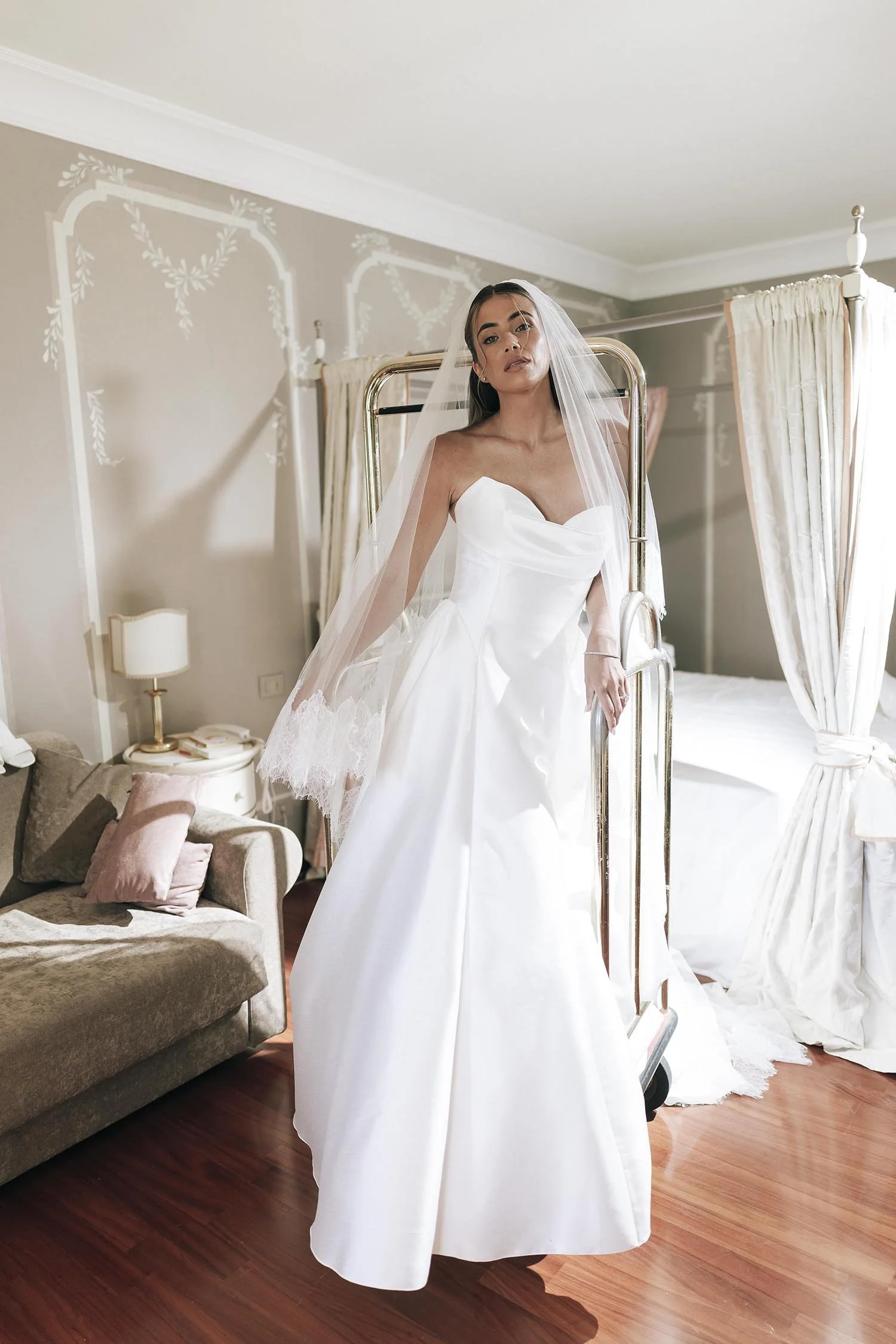 editorial photo of the bride in her dress standing on  a luggage cart in the bridal suite