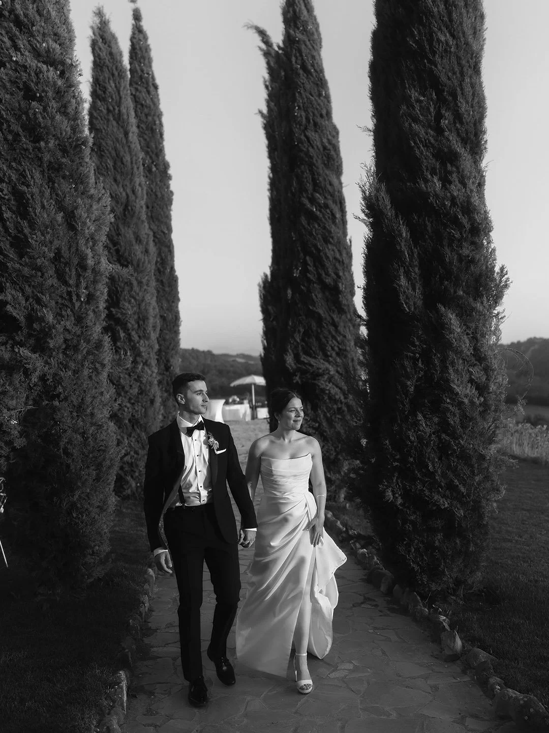 destination-wedding-tuscany-siena-borgo-laticastelli-photographer. bride and groom walking through the cypresses at sunset