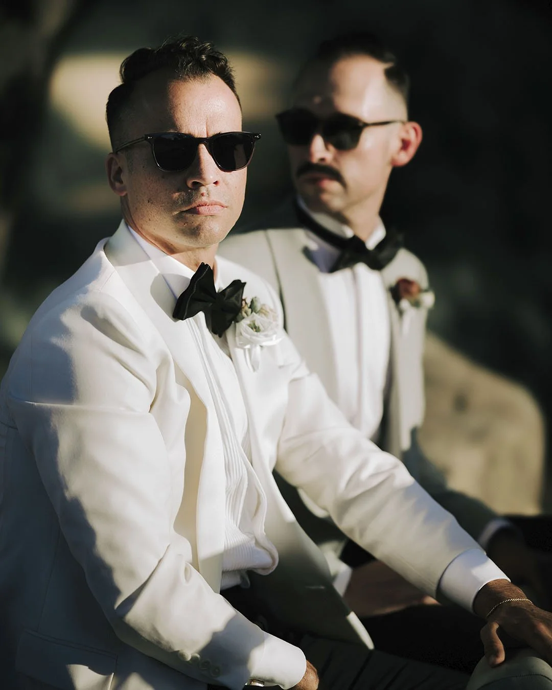 Two grooms on a vintage car at sunset