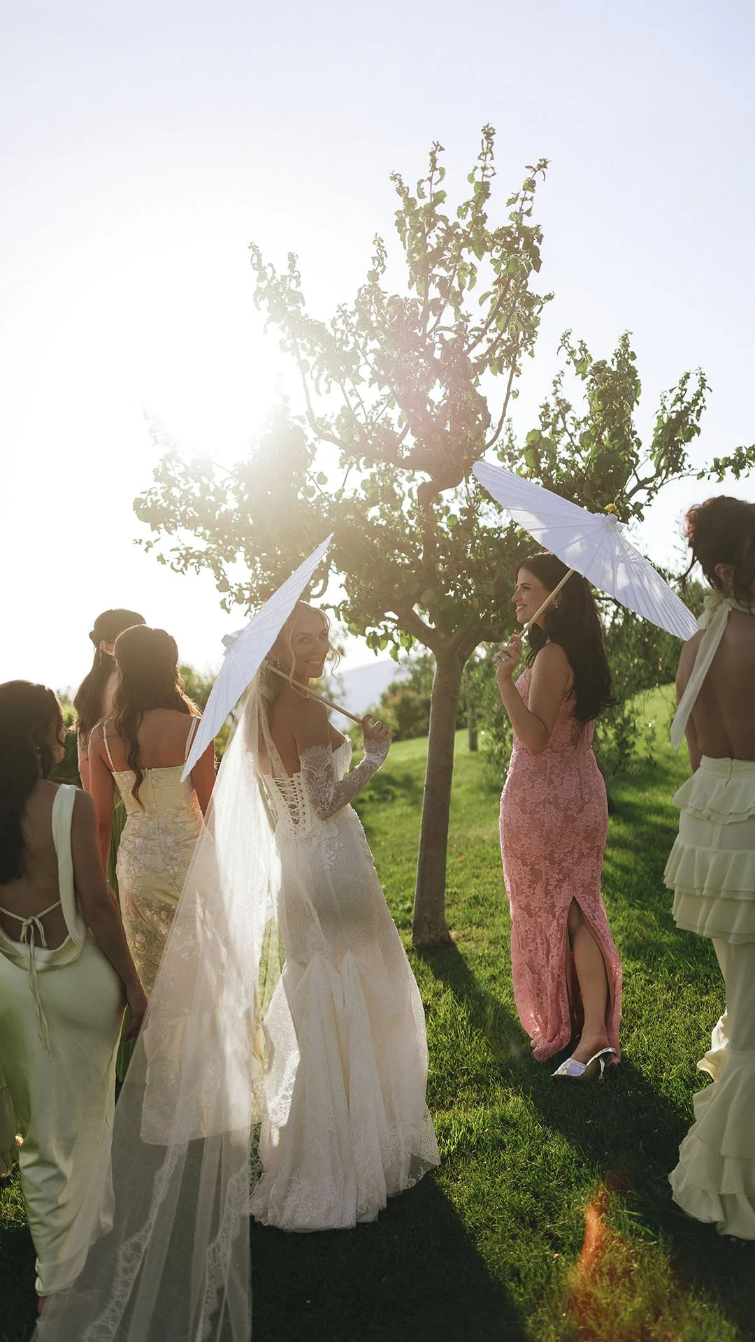 group photo of the bride with her bridesmaids holding parasole at sunset