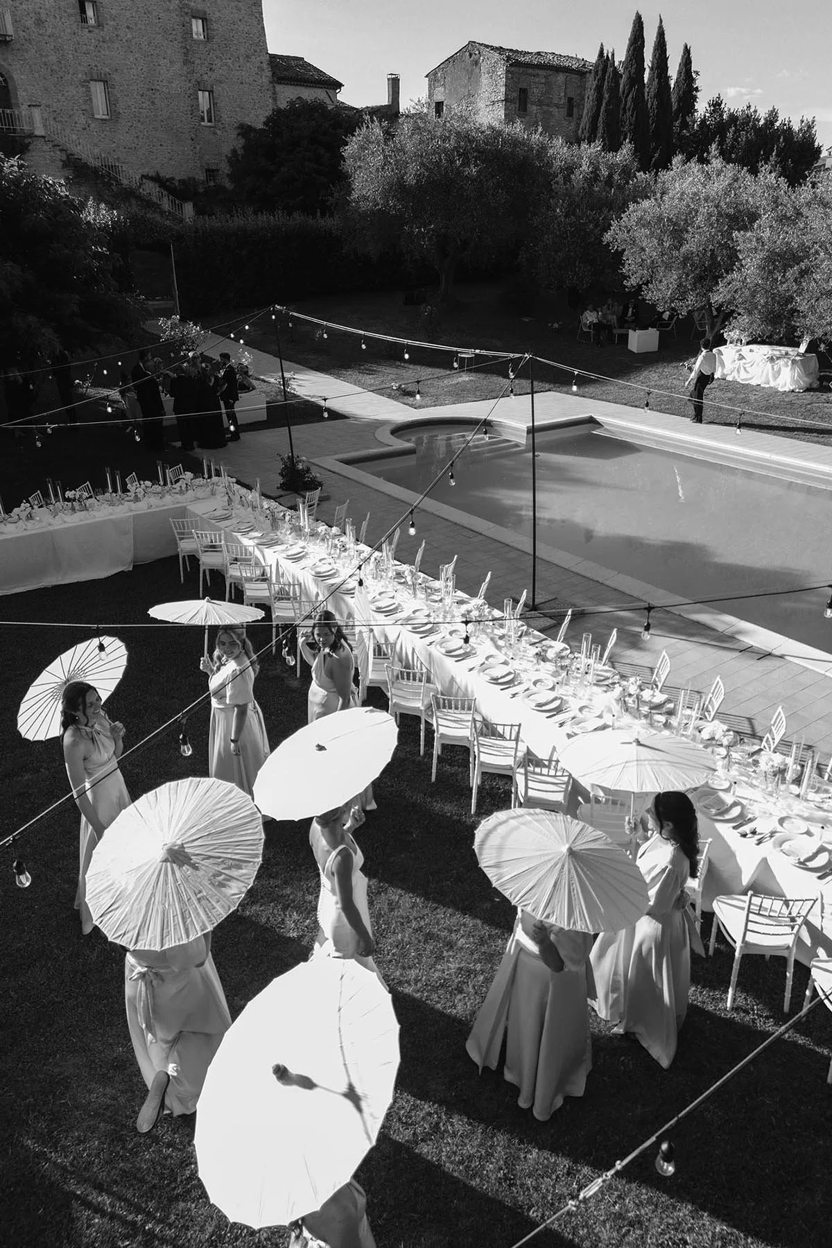aerial view of bride and bridesmaids holding parasoles by the dinner table at Castello di Montignano