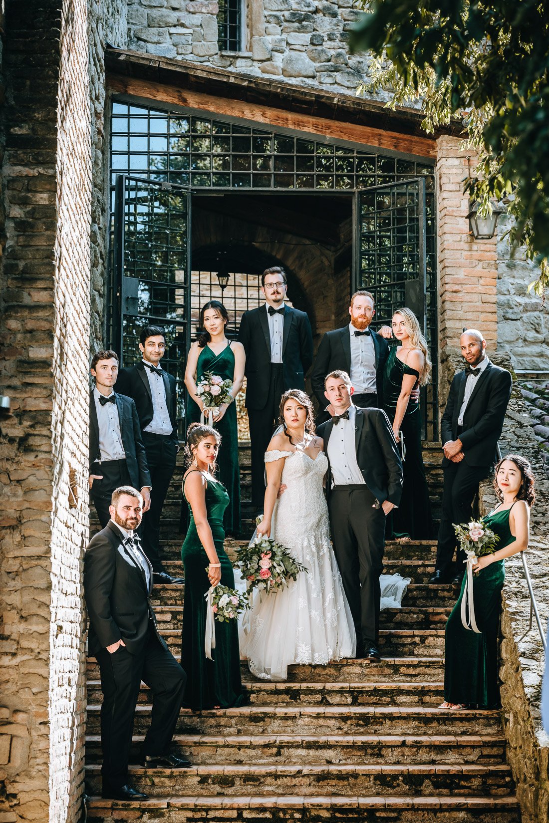 bridal party photo with bride and groom posing on the stairs of Castello di Rosciano with their groomsmen and bridesmaids