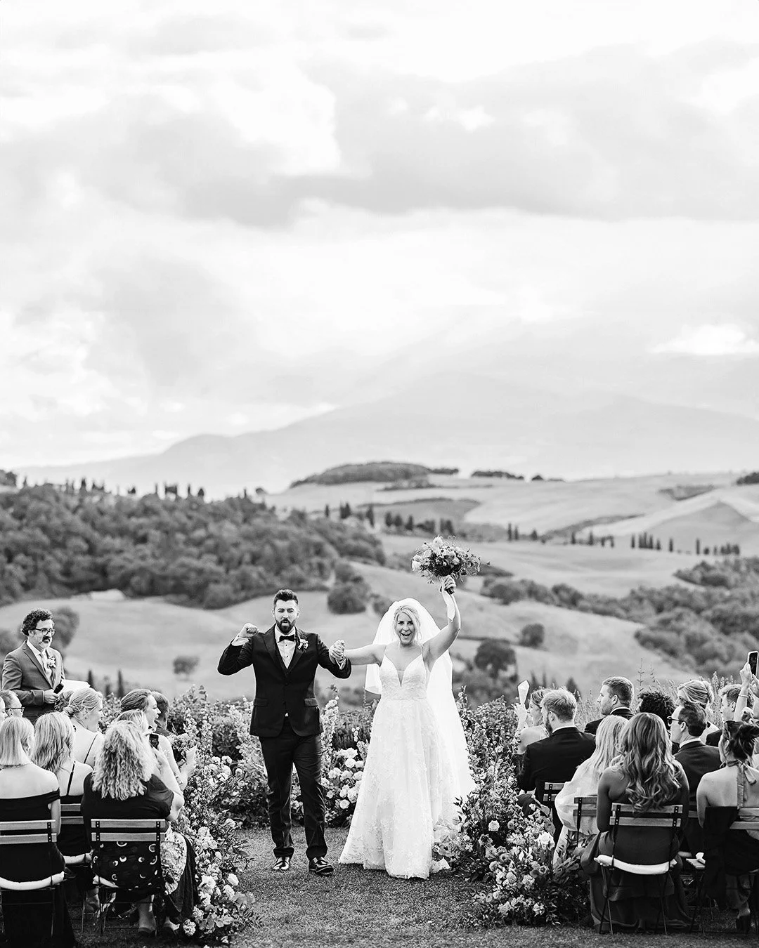 Bride and groom celebrate after the ceremony with Val d'Orcia hills in the background