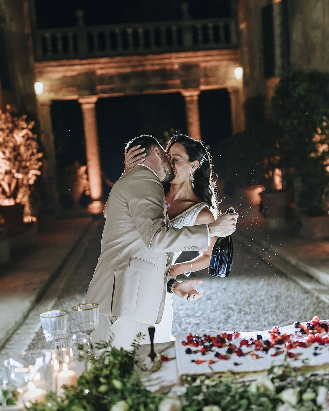 bride and groom kiss while cutting the cake