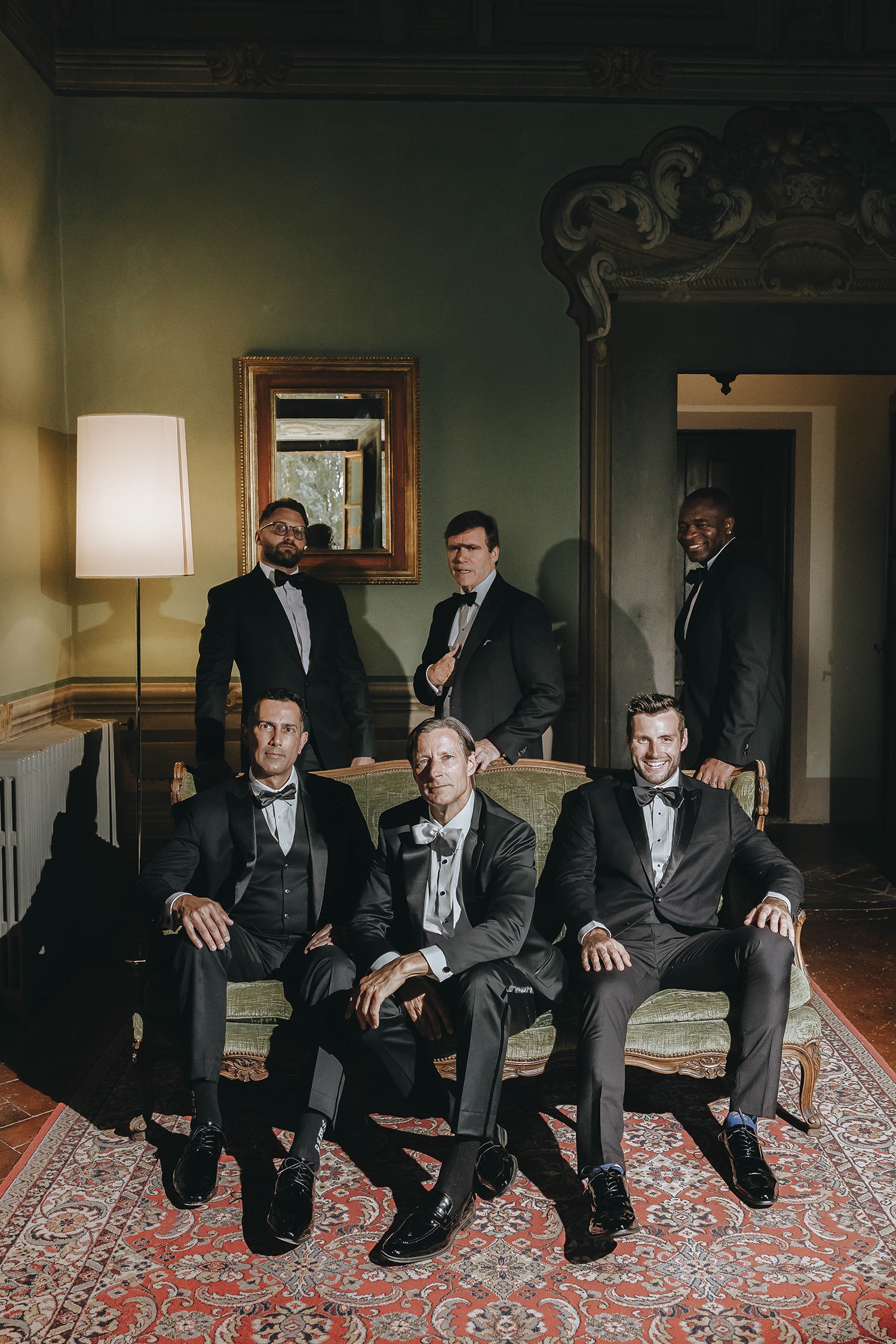 Destination wedding at Montegufoni castle near Florence in Tuscany. Editorial photo of the groom with his groomsmen in an old room of the castle