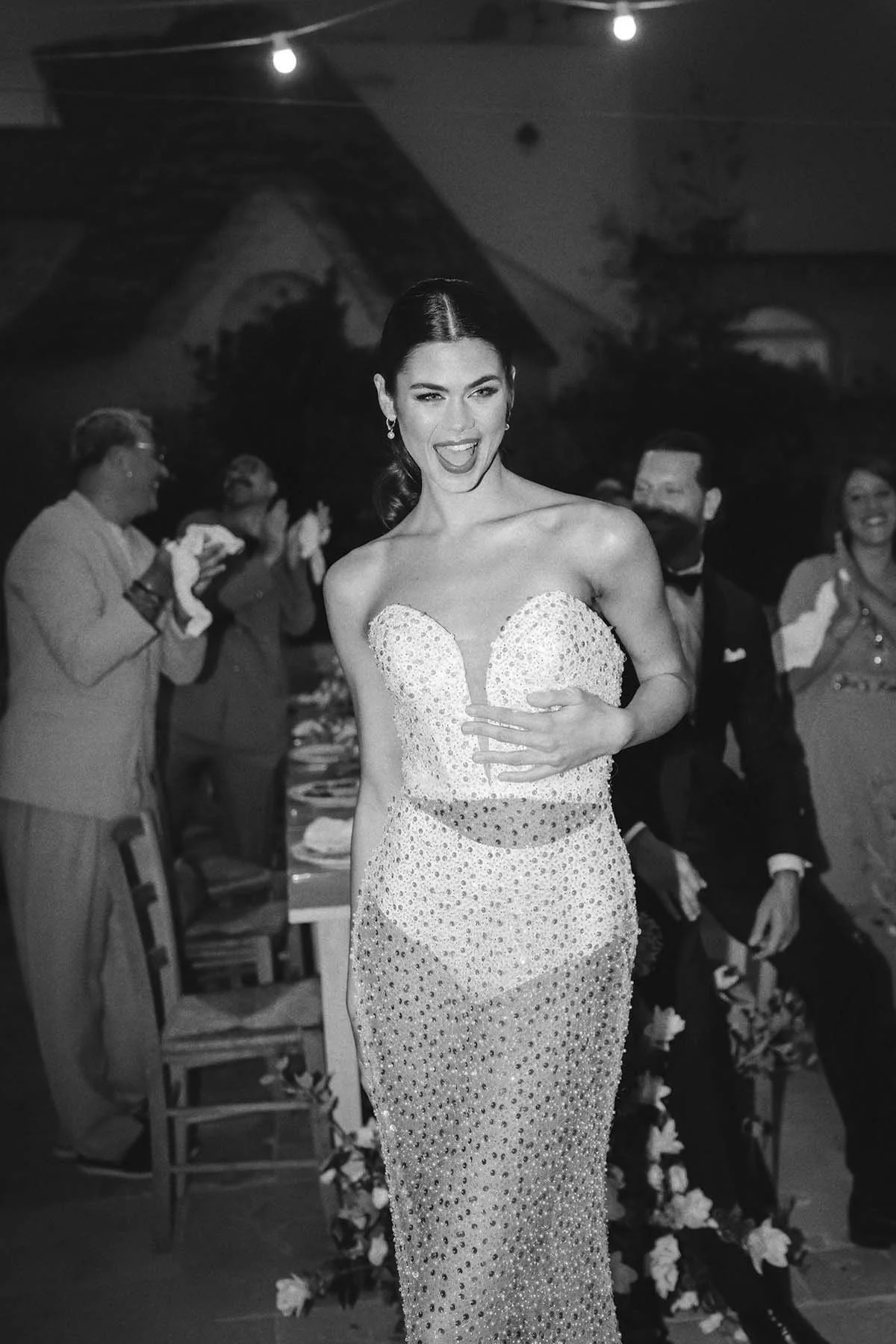 Portrait of a bride in her party dress having fun and smiling with guests celebrating in the background