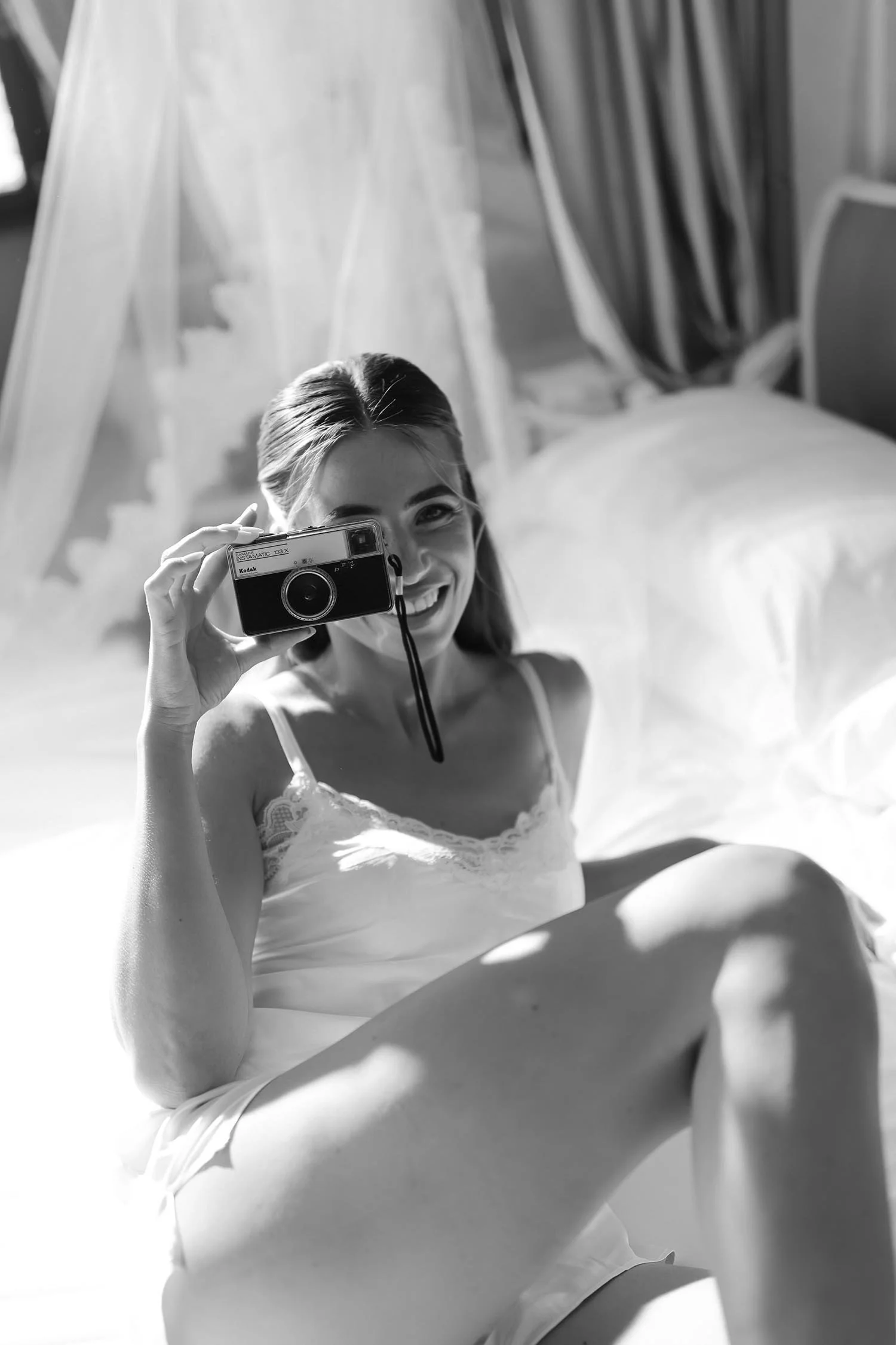 bride taking a photo with a disposable camera on the bed