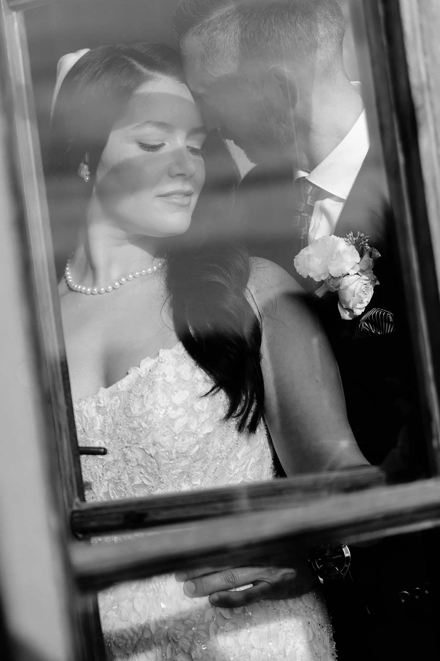 Groom and bride in an intimate pose taken through the window