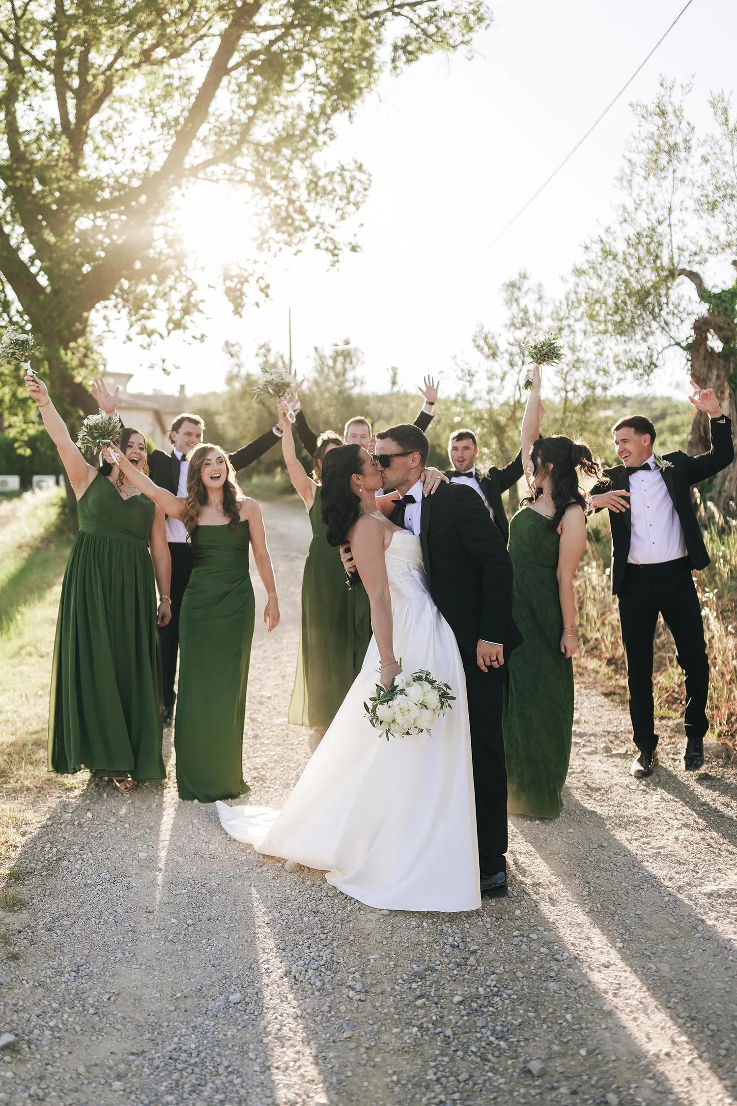 bride and groom kissing with their friends celebrating in the background