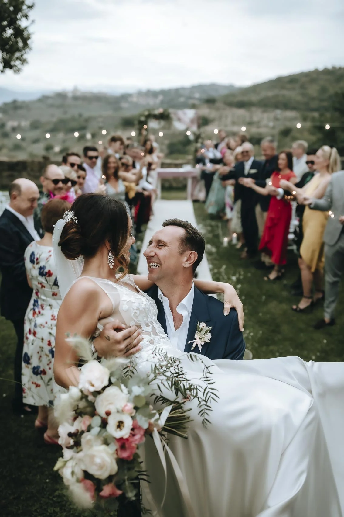 groom picking up his bride down the aisle at Castello di Rosciano