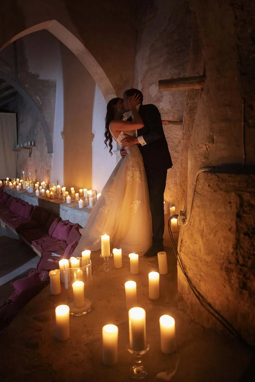 Moody photo of the bride and groom kissing with the light of the candles