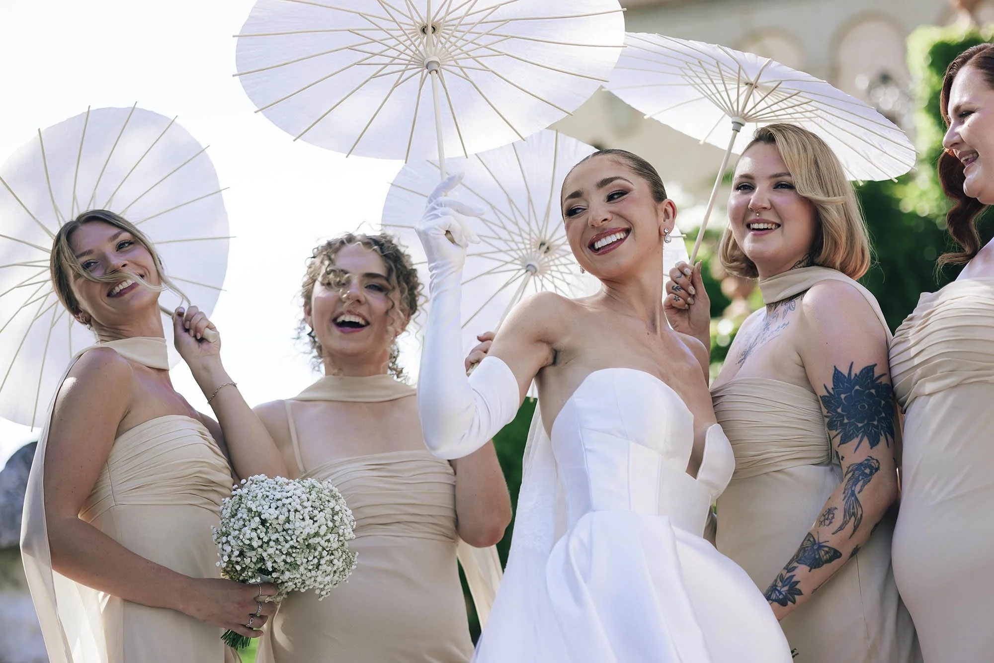 the bride posing with her bridesmaids holding parasoles